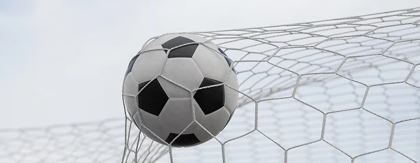 Gros plan sur un ballon de football qui frappe le filet du but, symbolisant un but marqué, la réussite et les moments décisifs d'un match de football.